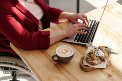 Woman-at-home-using-her-laptop-having-lunch-and-a-coffee